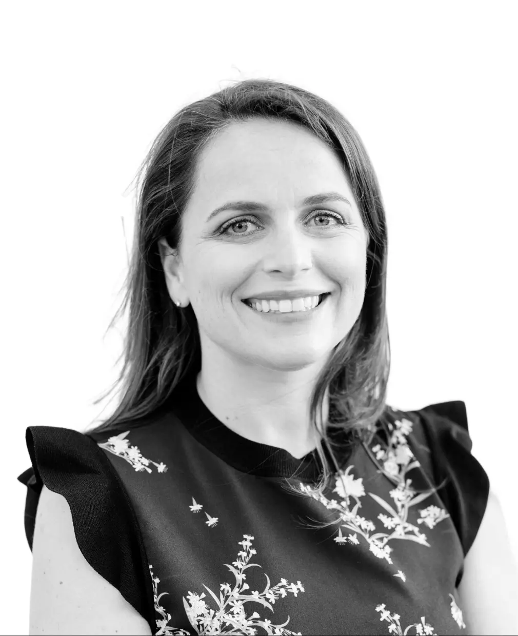 Black and white portrait of a woman with long dark hair and patterned shoulder details, smiling against white background.