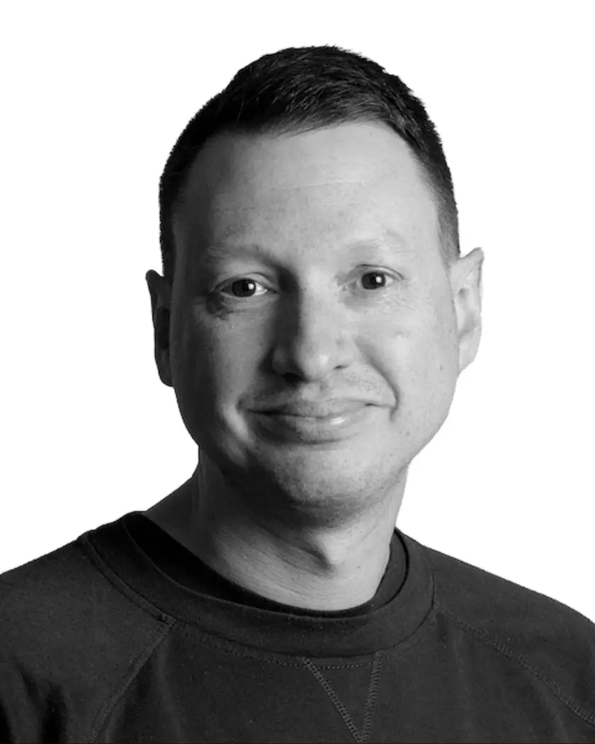 Black and white headshot portrait of a man in a dark shirt against white background.