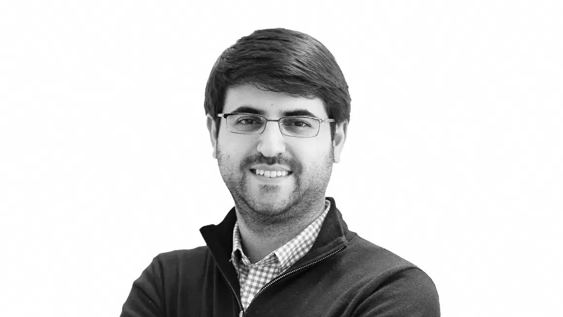 Professional headshot of man with glasses in checkered shirt