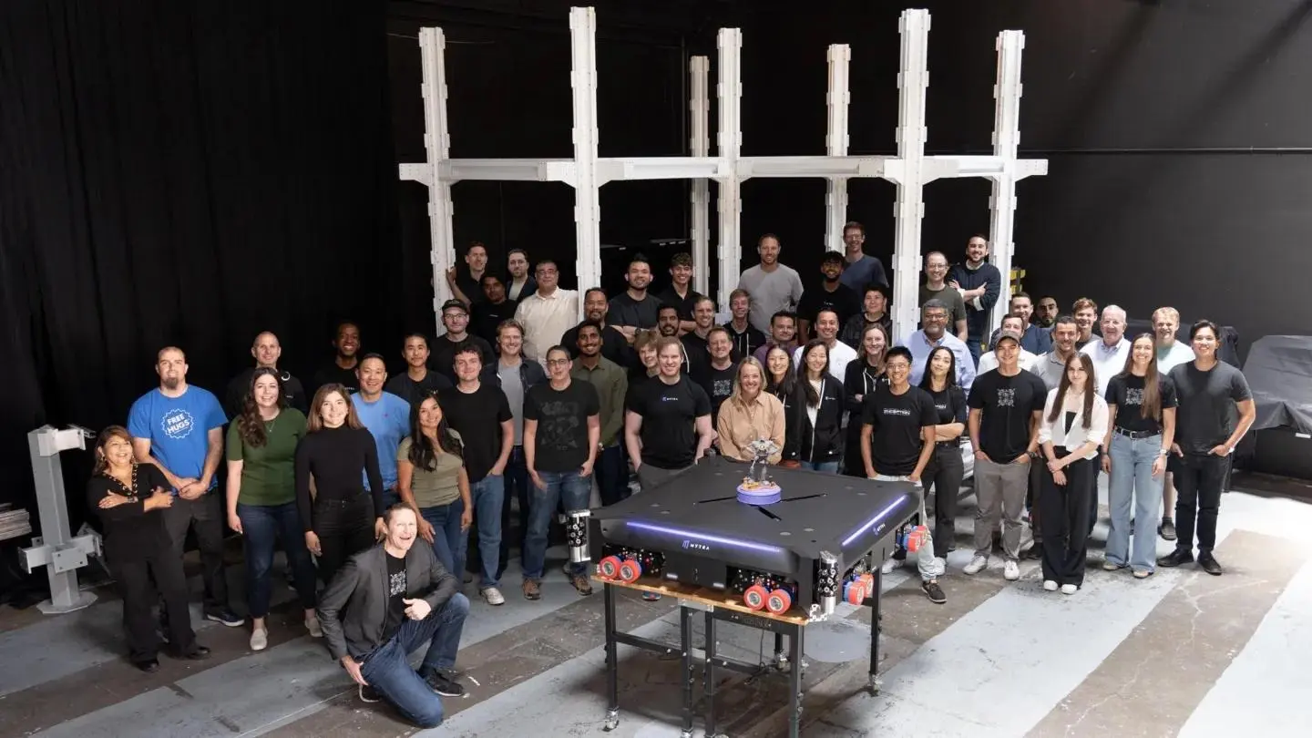 Group photo of diverse team standing in front of white cross structure