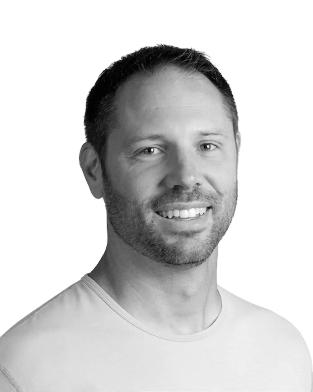Black and white headshot portrait of a man with beard smiling, against white background.