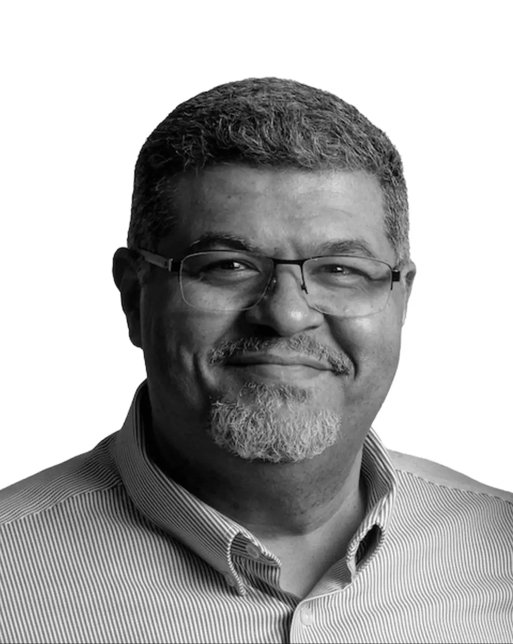Black and white headshot portrait of an older man wearing glasses with a beard, against white background.