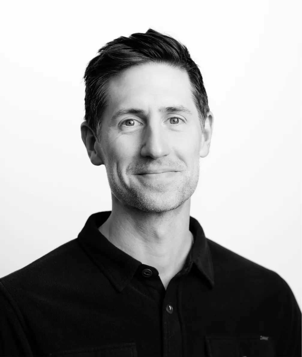 Black and white headshot portrait of a man in a dark polo shirt, against white background.